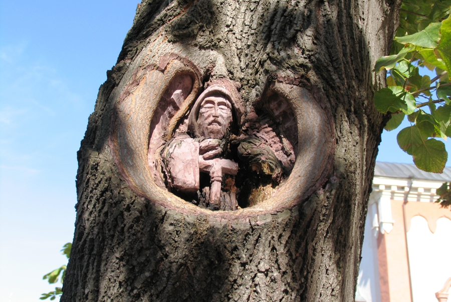 Фигура послушника, вырезанная в дупле дерева во дворе монастыря